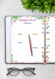 a planner with glasses on top of it next to a plant and eyeglasses