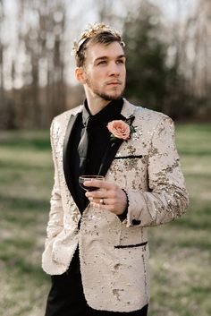 a man in a tuxedo holds a drink and looks off into the distance