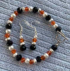 Orange, white and blackglass beads with silver accents. Lady Flyers fans will love this classy earring and bracelet set. Also great to add a classy touch to any Halloween sweater or top! Bracelet features a toggle clasp and is 8 inches from end to end. If a different size is needed, please email me. Elegant Beaded Halloween Jewelry, Elegant Beaded Jewelry For Halloween, Adjustable White Jewelry For Halloween, White Adjustable Jewelry For Halloween, White Dangle Jewelry For Halloween, White Czech Glass Dangle Jewelry, White Dangle Jewelry With Black Beads, Orange Dangle Jewelry With Black Beads, Silver Round Beads Jewelry For Halloween