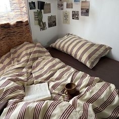 a bed with striped sheets and pillows in a bedroom next to pictures on the wall