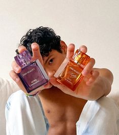 a man holding two different perfume bottles in front of his face