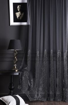 a black and white room with curtains, a lamp and pictures on the wall