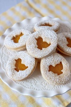 several powdered sugar covered cookies on a white plate with yellow checkered tablecloth