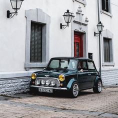 a small black car parked in front of a white building