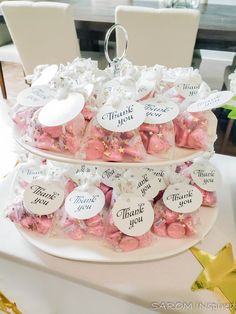 two tiered trays filled with pink and white candies on top of a table