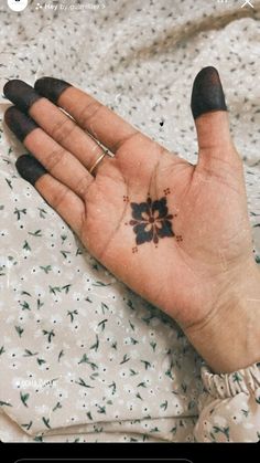 a person's hand with a small flower tattoo on the middle of their palm