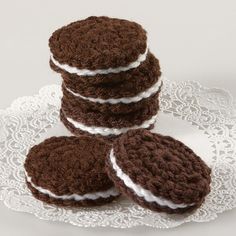 four crocheted cookies sitting on top of a white doily