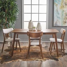 a dining room table with chairs and a potted plant in the corner next to it