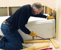 a man in black shirt and yellow gloves working on an unfinished mattress with construction tools