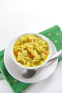 a white bowl filled with noodles and carrots on top of a green place mat