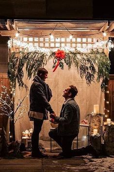 two men sitting on the ground in front of a christmas display with lights and decorations