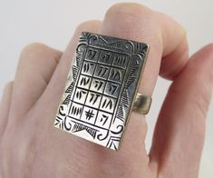 "A gridded tablet engraved with Runic, Sanskrit or an unknown ancient language tops this vintage sterling silver ring. The large rectangular 1 1/16 inch x 3/4 inch face is carved with fifteen letters or numbers. Linear and scrolled markings frame the characters. The ring was finished with a 4.9mm wide thick sterling band. The ring tested as sterling silver purity (no identifying hallmarks) and measures an approx. size 9.75. It could be re-sized by an experienced jeweler. The ring is in very good Handmade Rectangular Sterling Silver Engraved Ring, Unique Rectangular Engraved Rings, Handmade Silver Engraved Rectangular Ring, Rectangular Silver Engraved Ring Stamped 925, Ancient Alphabet, Dua Images, Zakir Hussain, Ancient Alphabets, Ancient Languages