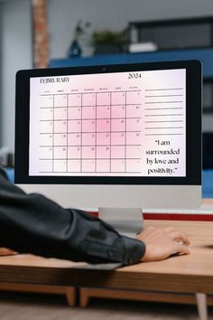 a person sitting at a desk in front of a computer monitor with a calendar on it