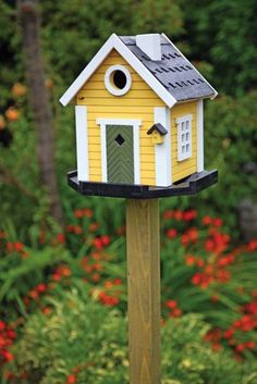 a yellow bird house on top of a wooden post