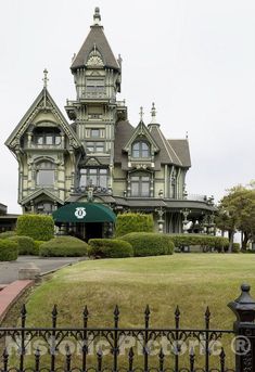 a large house with many windows and lots of green grass in front of the fence