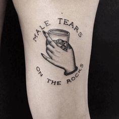 a tattoo on the leg of a woman with a glass in it that says, male tears on the rocks