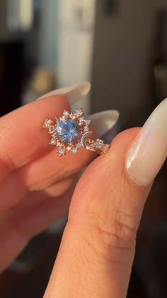 a woman's hand holding an engagement ring with blue and white diamonds on it