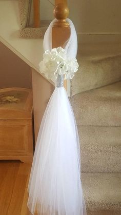 a white wedding dress with flowers on the front and back, sitting on top of some stairs