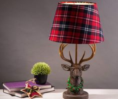 a lamp with a deer head on it next to a potted plant and book