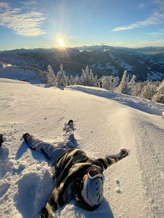 a person laying in the snow on top of a mountain