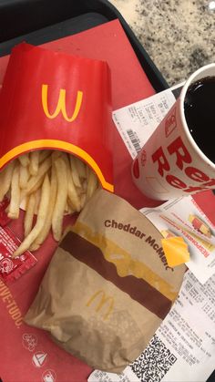 a tray with french fries and a mcdonald's bag next to a cup of coffee