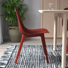 two red chairs sitting on top of a rug next to a white table and chair