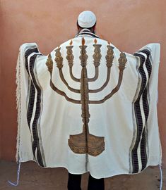 a man wearing a hanukkah shawl in front of a wall