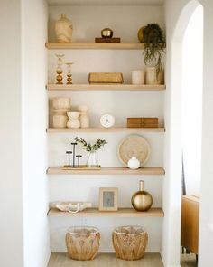 the shelves are filled with vases, bowls and other decorative items in white walls