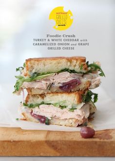 two halves of a turkey sandwich stacked on top of each other with grapes and lettuce