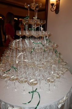 a table topped with lots of wine glasses filled with champagne and green ribbon tied around the rims