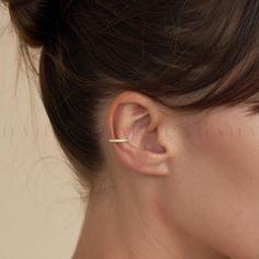 a close up of a woman's ear wearing a gold nose ring