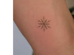 a small snowflake tattoo on the back of a woman's arm and leg