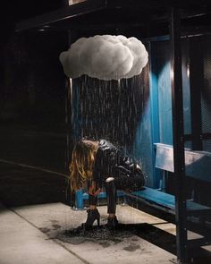 a person sitting on a bench in the rain under a cloud hanging from their head