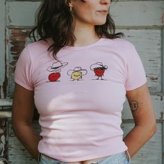 Our Bad Fruit Baby Crop Tee is printed on a pink women's LA Apparel classic crew neck baby tee with black, yellow and red ink. This tee is a fun and spicy baby tee with a mid-length cropped fit and pairs perfectly with jeans or shorts. Not all cowboys are cut from the same sturdy cloth; some are bad to the bone, like these bad fruits! Cheap Cherry Charlie, Lousy Lemon Larry, and Stinky Sam Strawberry! This classic tee is ready to be worn on a hike, to your favorite lunch spot or the library. The design is printed on the front center of the shirt. Design by Tatum Johnson in Bozeman, Montana. Made in the USA 1x1 baby tee • 100% Cotton Bad Fruit, La Apparel, Fruit Baby, La Outfits, Bozeman Montana, To The Bone, Bad To The Bone, Bandana Scarf, Red Ink