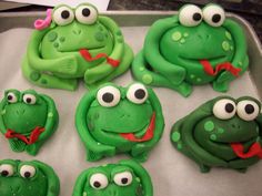 there are many green cookies with eyes and mouths on the cookie sheet in the shape of frogs