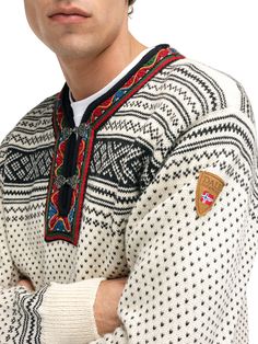 a man with his arms crossed wearing an ugly sweater and looking off to the side