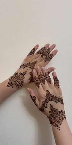 two hands with henna tattoos on them