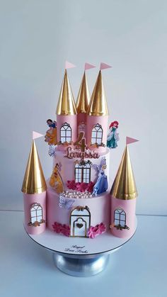 a pink and gold castle cake with princess figurines on the top tiers