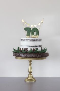 a white and brown cake sitting on top of a gold plated stand with the number 70 on it