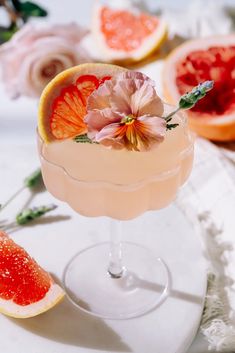 a glass filled with a drink next to slices of grapefruit