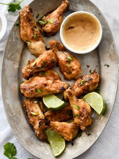 chicken wings on a plate with dipping sauce and cilantro garnishes