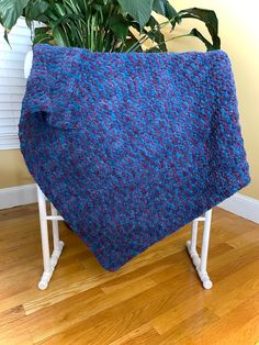 a blue blanket sitting on top of a wooden floor next to a potted plant