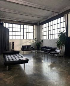 an empty room with black leather furniture and large windows