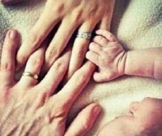 an older person holding the hands of a baby's hand while it lays down