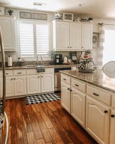 a kitchen with white cabinets and wood floors