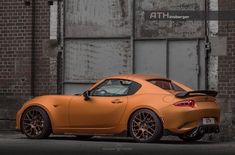 an orange sports car parked in front of a brick building with graffiti on the wall