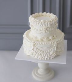 a three tiered white wedding cake sitting on top of a table