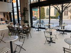 an empty restaurant with tables and chairs in front of large windows looking out onto the street