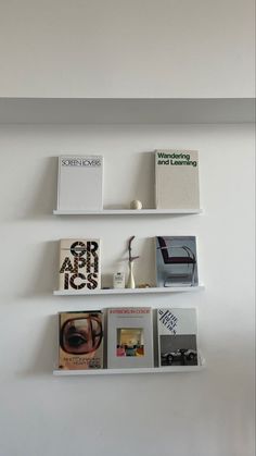 three white shelves with books on them against a wall