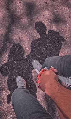 two people standing next to each other with shadows on the ground in front of them